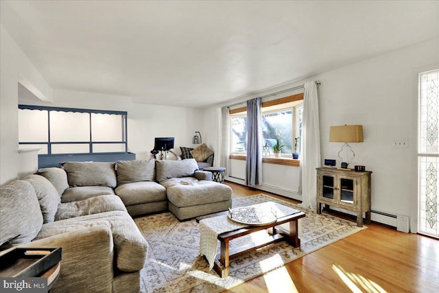 living room featuring plenty of natural light, light hardwood / wood-style floors, and a baseboard heating unit