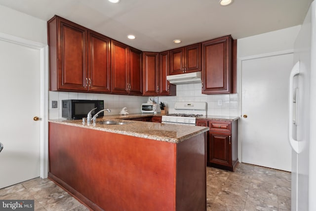 kitchen with white appliances, backsplash, sink, light stone counters, and kitchen peninsula