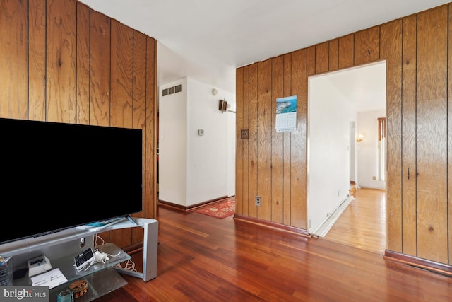 unfurnished living room with wooden walls and dark wood-type flooring