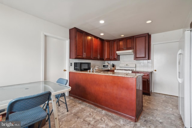 kitchen with decorative backsplash, kitchen peninsula, light stone counters, white appliances, and sink