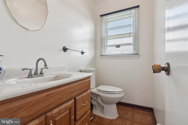 bathroom with vanity, toilet, and parquet flooring