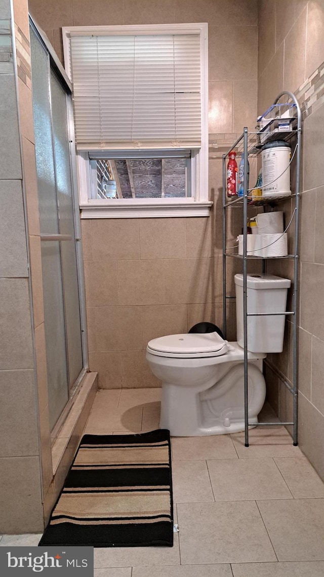 bathroom featuring walk in shower, tile patterned flooring, tile walls, and toilet