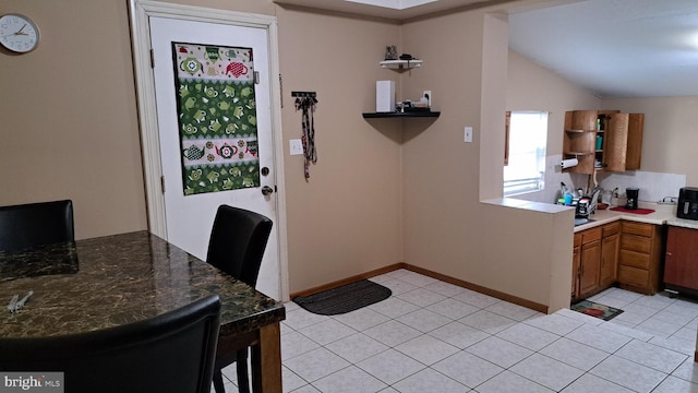 interior space with a breakfast bar, lofted ceiling, and light tile patterned floors