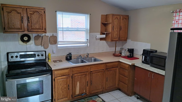 kitchen with appliances with stainless steel finishes, backsplash, sink, light tile patterned floors, and lofted ceiling