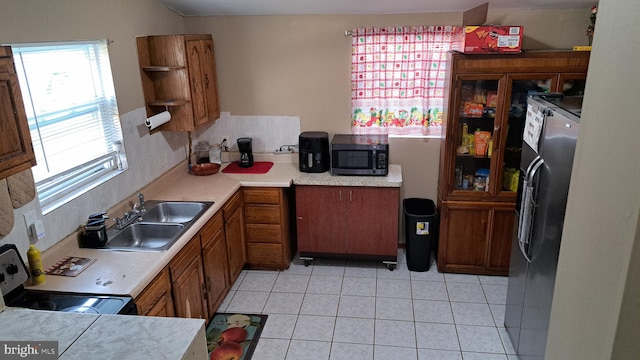 kitchen featuring decorative backsplash, sink, light tile patterned floors, and stainless steel appliances