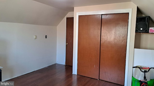 unfurnished bedroom with vaulted ceiling, dark hardwood / wood-style flooring, and a closet