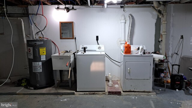 laundry room featuring electric water heater, separate washer and dryer, and sink