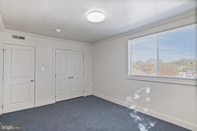 unfurnished bedroom with dark colored carpet and ornamental molding