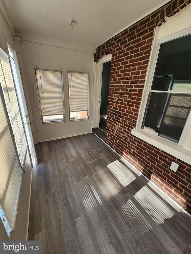 interior space with brick wall and dark hardwood / wood-style floors