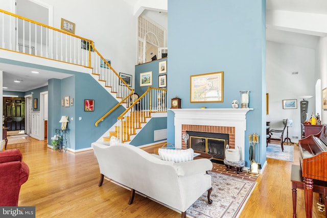 living room featuring hardwood / wood-style flooring, crown molding, a towering ceiling, and a fireplace