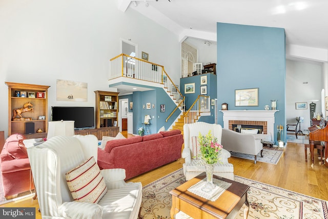 living room featuring a fireplace, light wood-type flooring, and high vaulted ceiling