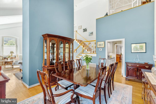 dining room with high vaulted ceiling and light hardwood / wood-style flooring