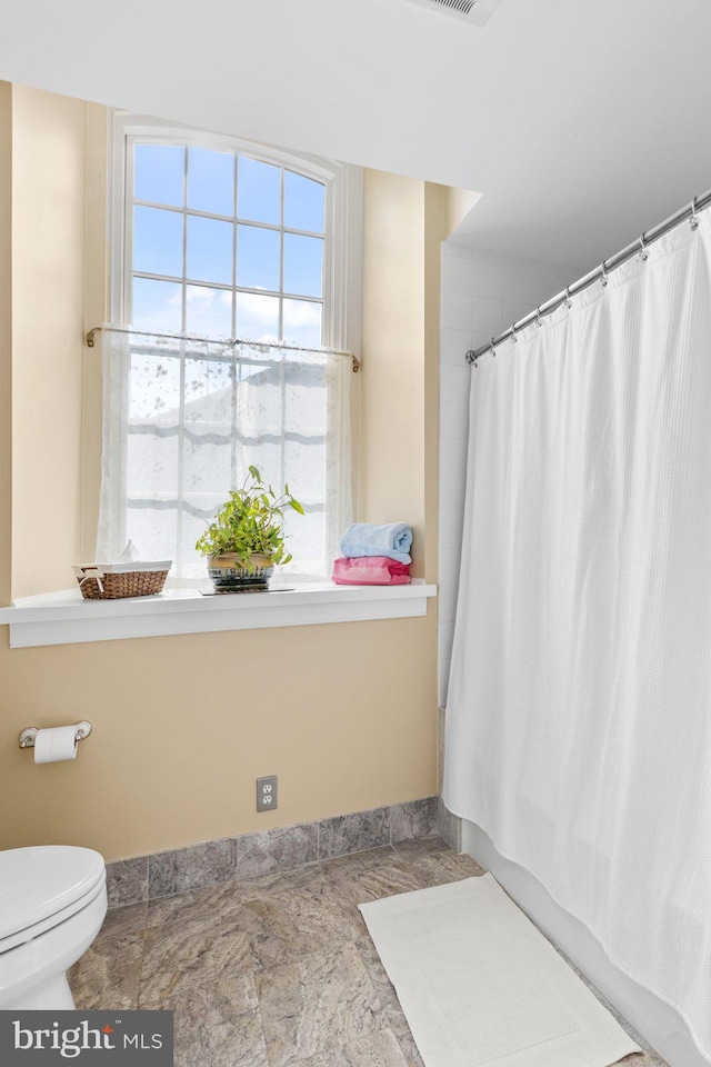 bathroom with toilet and shower / tub combo with curtain