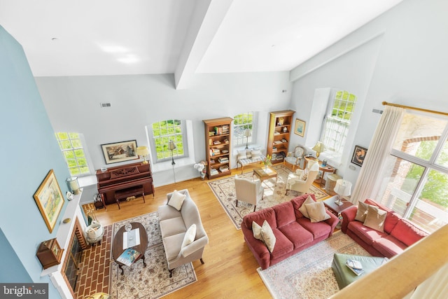 living room featuring beam ceiling, high vaulted ceiling, and light hardwood / wood-style floors