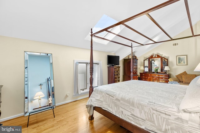 bedroom with light hardwood / wood-style flooring and lofted ceiling with skylight