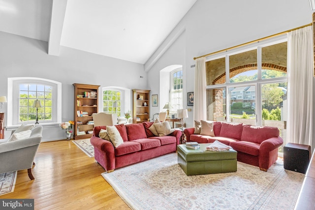 living room featuring hardwood / wood-style floors, a healthy amount of sunlight, beamed ceiling, and high vaulted ceiling