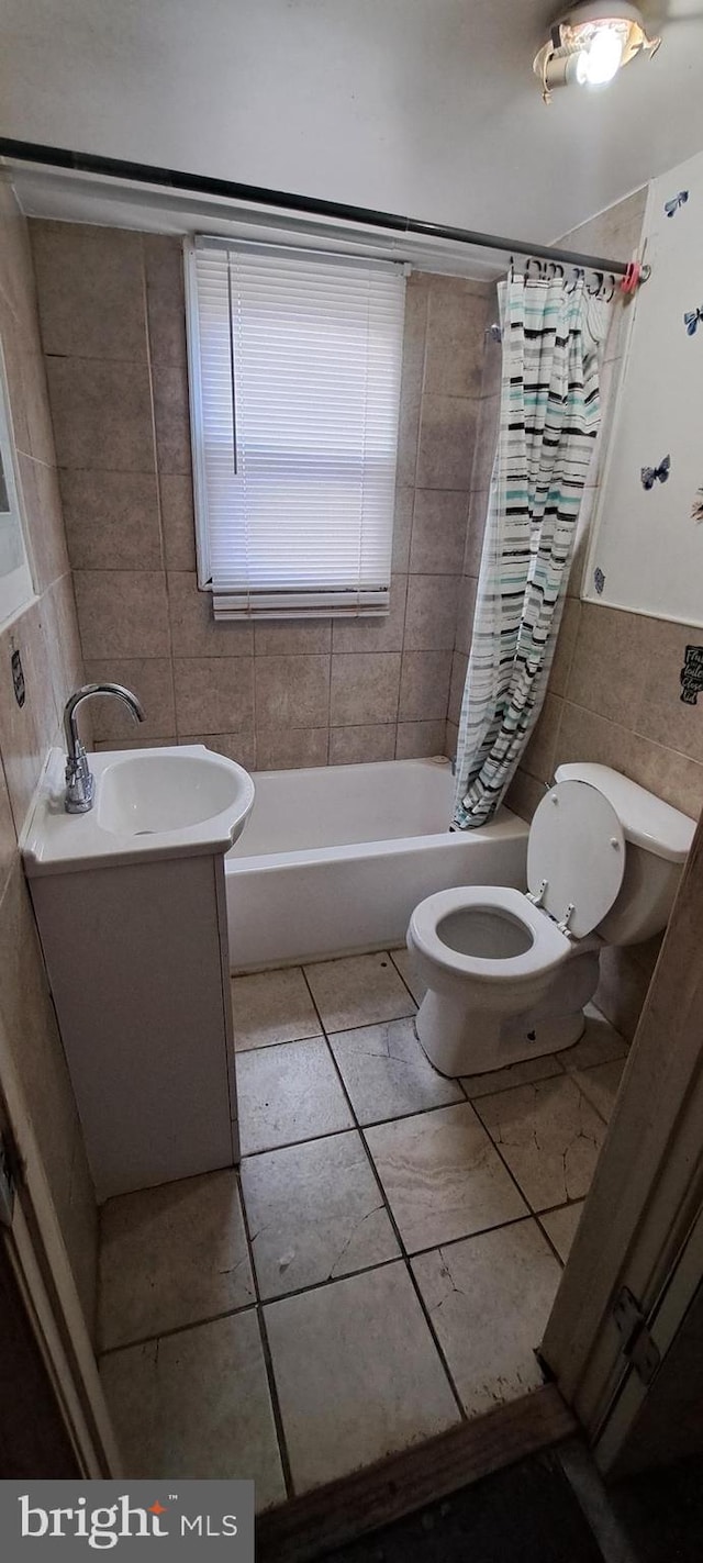 full bathroom with shower / tub combo, tile patterned floors, vanity, tile walls, and toilet