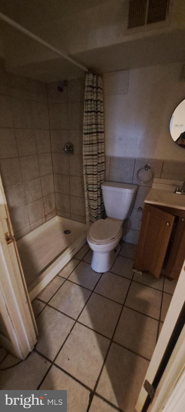 bathroom with tile patterned flooring, toilet, tile walls, and a shower with shower curtain