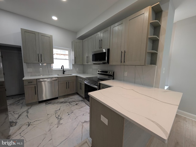 kitchen featuring sink, stainless steel appliances, tasteful backsplash, kitchen peninsula, and gray cabinets