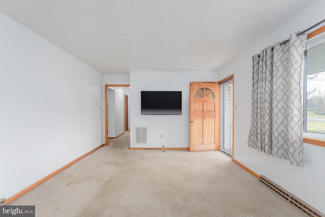 unfurnished living room with carpet flooring, a textured ceiling, and baseboard heating