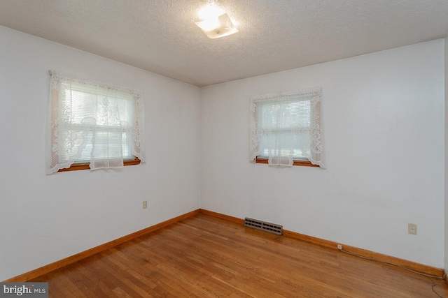 spare room featuring a textured ceiling and hardwood / wood-style flooring