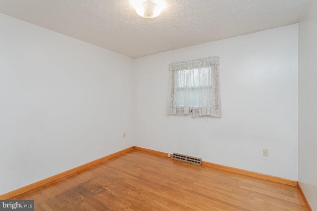 spare room featuring wood-type flooring and a textured ceiling