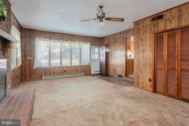 unfurnished living room featuring ceiling fan, a baseboard heating unit, carpet floors, a textured ceiling, and a fireplace