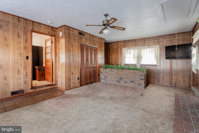 interior space with carpet, ceiling fan, and wood walls