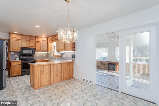 kitchen featuring sink, an inviting chandelier, backsplash, kitchen peninsula, and black appliances