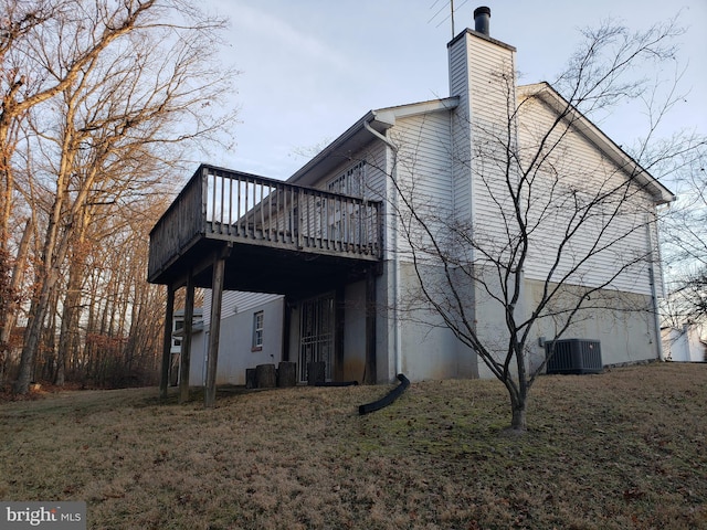 view of side of home with a wooden deck, central AC, and a lawn