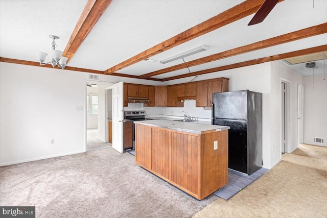 kitchen featuring beam ceiling, sink, black fridge, a kitchen island with sink, and stainless steel range with electric cooktop