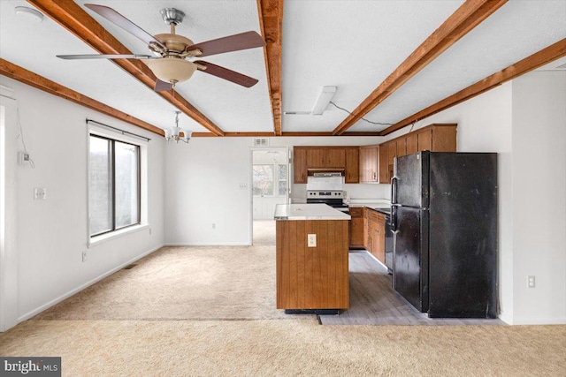 kitchen with a center island, electric range, black refrigerator, and a healthy amount of sunlight