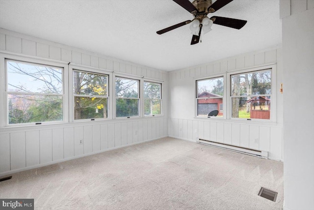 unfurnished sunroom with plenty of natural light, a baseboard heating unit, and ceiling fan