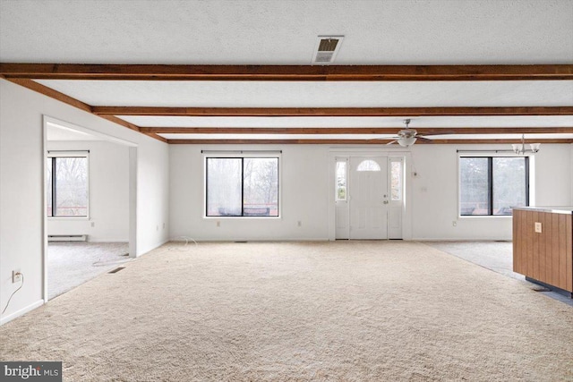 unfurnished living room featuring plenty of natural light, ceiling fan, a textured ceiling, and light carpet