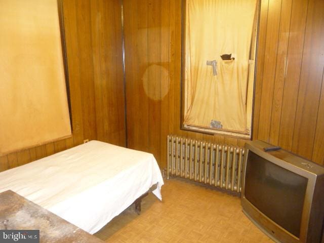 bedroom featuring radiator heating unit and light parquet flooring