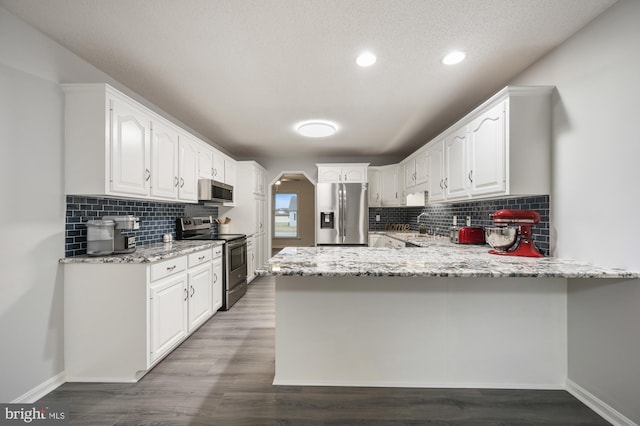 kitchen featuring kitchen peninsula, stainless steel appliances, white cabinetry, and hardwood / wood-style flooring