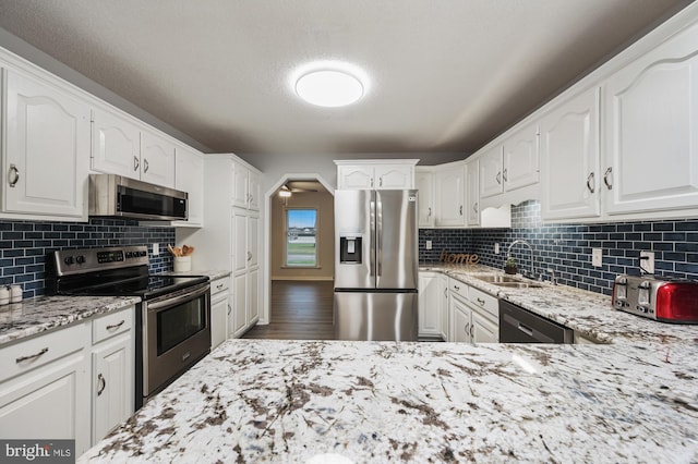 kitchen featuring white cabinetry, sink, ceiling fan, light stone counters, and appliances with stainless steel finishes