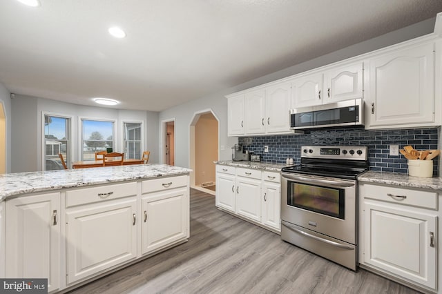 kitchen featuring tasteful backsplash, light stone countertops, white cabinets, and stainless steel appliances