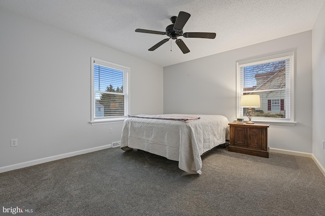 carpeted bedroom featuring multiple windows, ceiling fan, and a textured ceiling