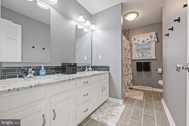 bathroom featuring tile patterned flooring, vanity, toilet, and a textured ceiling