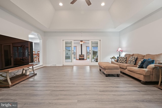 living room featuring ceiling fan, light wood-type flooring, and a tray ceiling