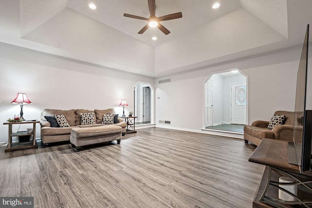 living room featuring a raised ceiling, ceiling fan, high vaulted ceiling, and wood-type flooring