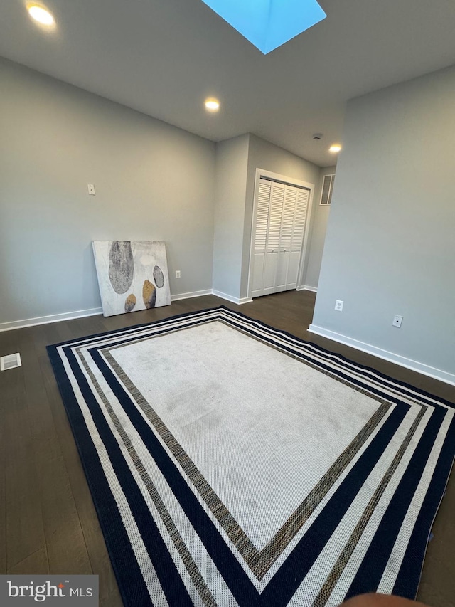 unfurnished bedroom featuring a skylight, dark wood-type flooring, and a closet