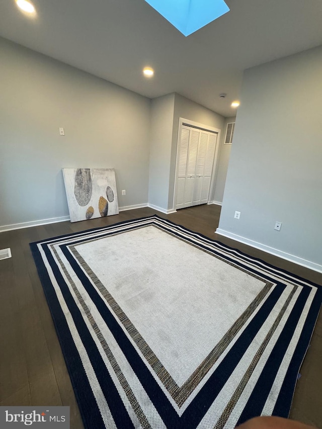 interior space with dark hardwood / wood-style flooring and a skylight