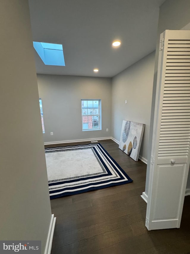 interior space with dark hardwood / wood-style flooring and a skylight