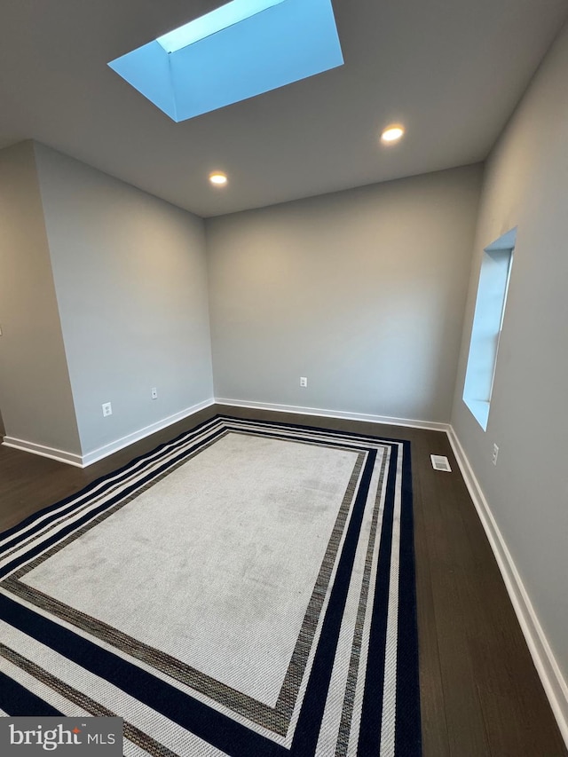 spare room featuring wood-type flooring and a skylight