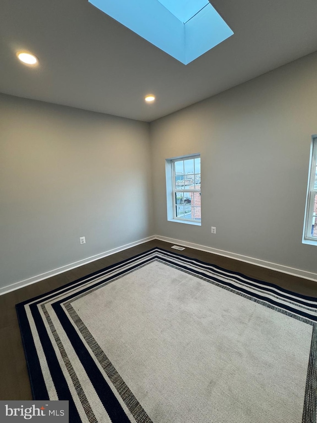 unfurnished room with hardwood / wood-style floors and a skylight