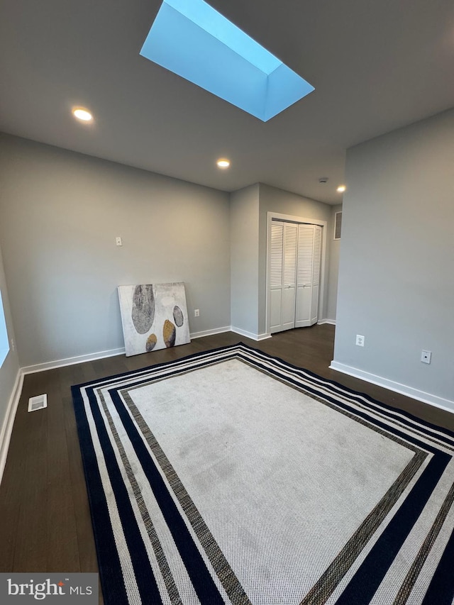 interior space featuring a skylight, a closet, and dark wood-type flooring