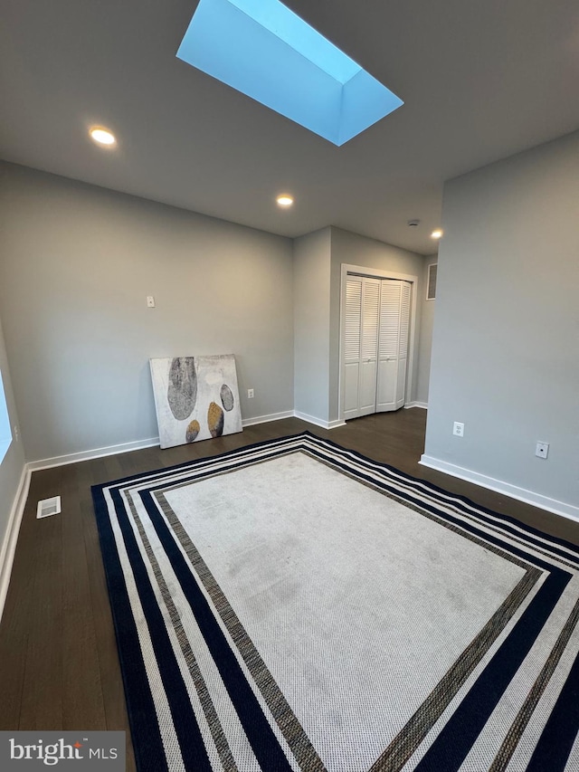 spare room featuring a skylight and dark hardwood / wood-style floors