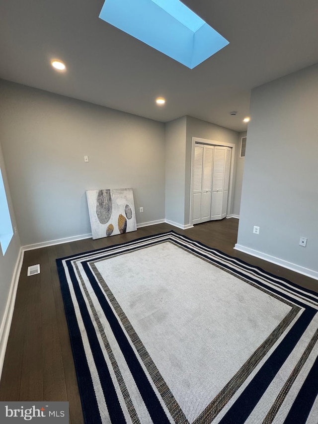 empty room featuring dark hardwood / wood-style floors and a skylight